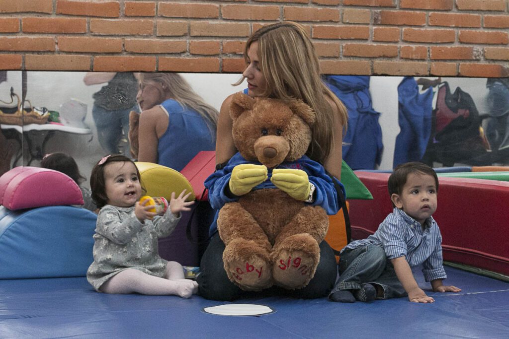 A woman, representing Baby Signs Mexico, lovingly cradles a teddy bear in her arms.