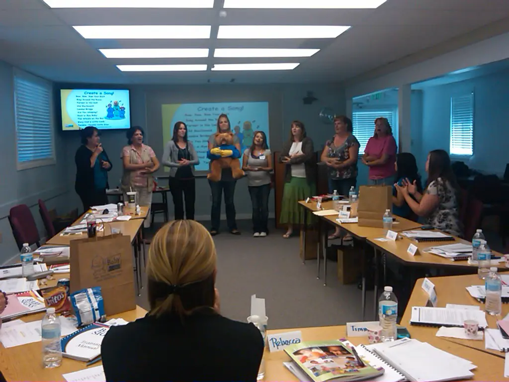 A group of people teaching baby sign language in a conference room.