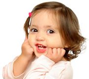 Toddler girl with brown hair smiling, hands on cheeks demonstrating baby sign language, pink hair clip, on white background.