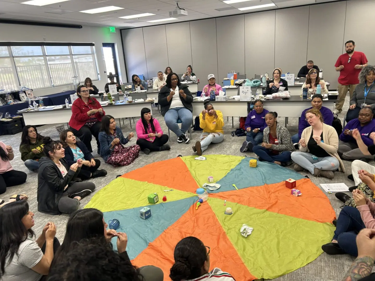 Group of people sitting on colorful parachute.