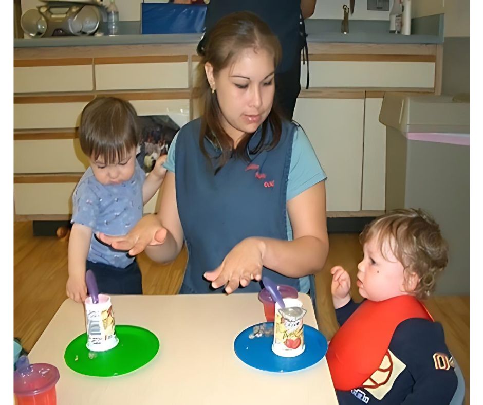 Woman feeding toddlers at a table.