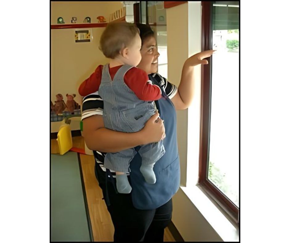 Woman holding a baby looks out window.