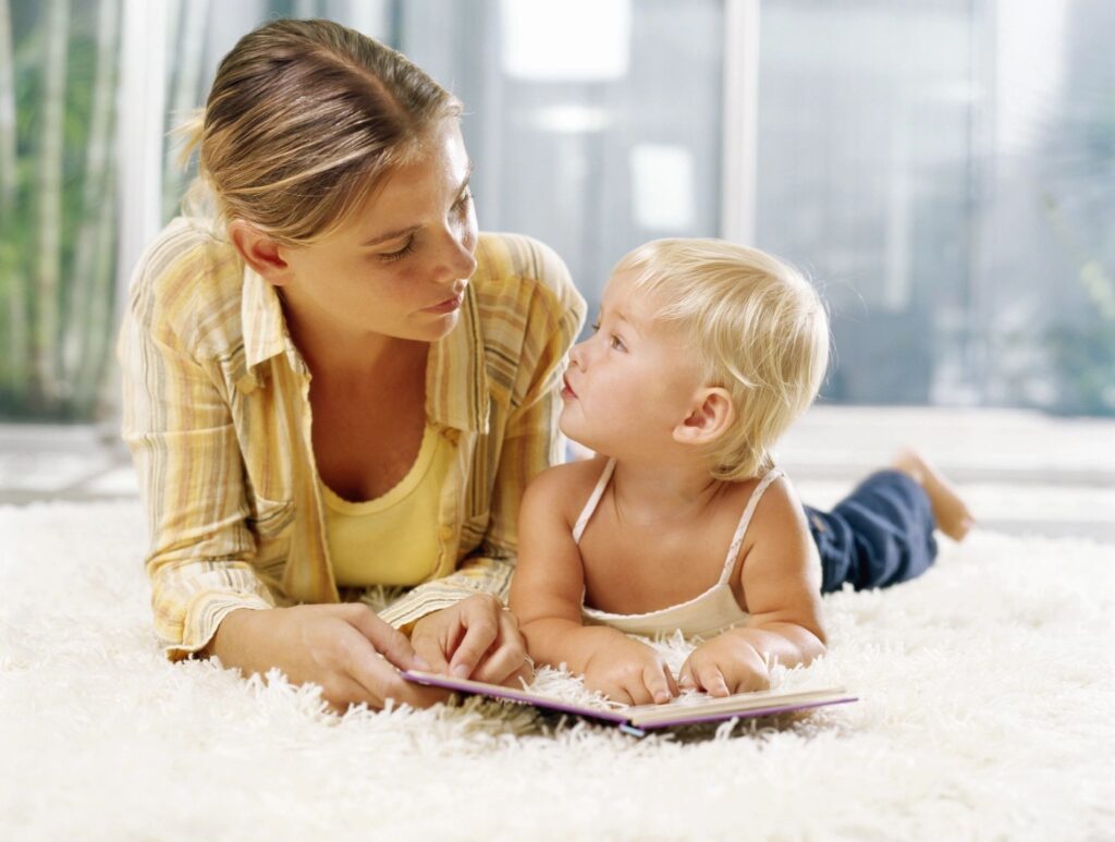 Woman and toddler reading a book together.