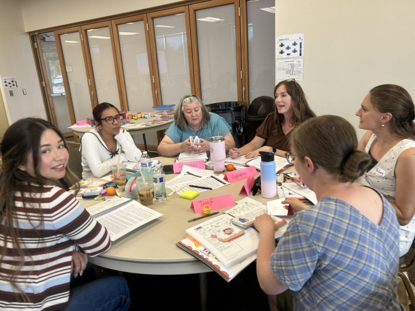 Participants working together around a table with Baby Signs® training materials during the 2-Day Instructor Training.